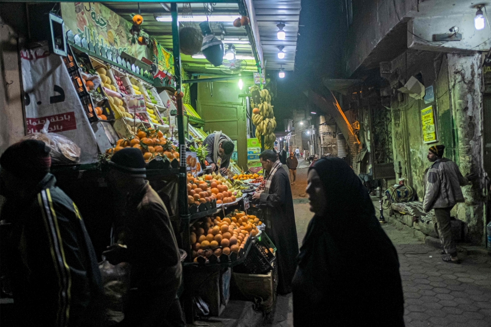 People walk past a fruit seller's stall in the Azhar district in Cairo January 16, 2023. — AFP pic