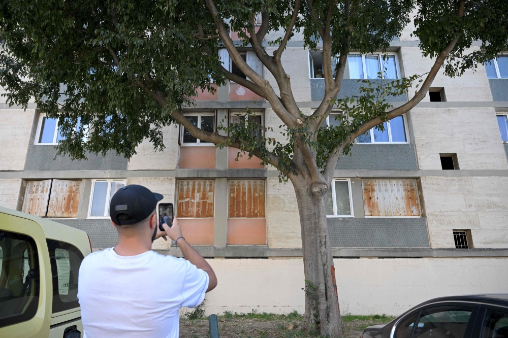 A man takes pictures of a building in the 10th district of Marseille on September 11, 2023, where a woman was shot inside her apartment by gunshots fired from the street the day before.— AFP pic