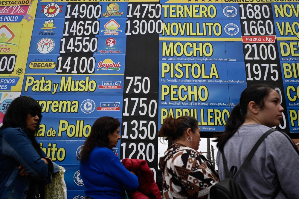 People line up in front of a butcher shop next to signs with meat prices in Buenos Aires on September 11, 2023. — AFP pic