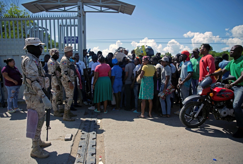 Dominican soldiers stand guard as Haitian citizens cross the gate at the Dominican Republic-Haiti border, in Dajabon, Dominican Republic. — AFP pic