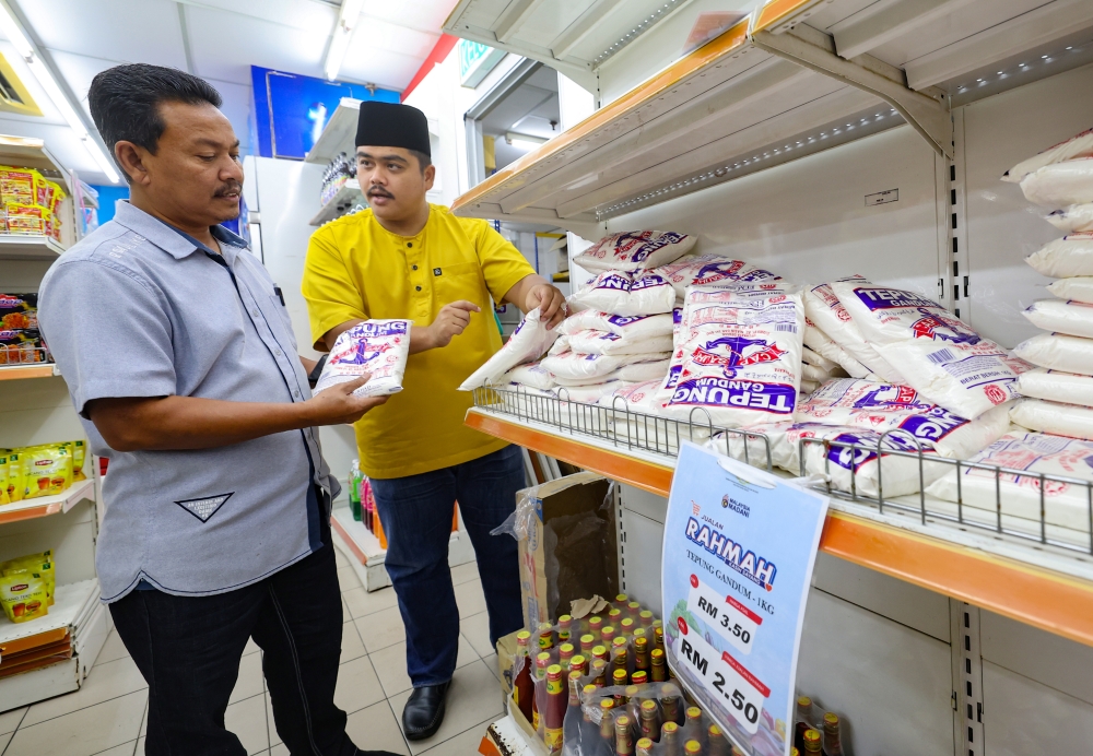 Entrepreneur Muhamad Hilmi Mohamed Shaari (right) watches as KSKK economic bureau head Wan Mohd Marzuki Wan Abdul Kadir inspects the price of flour at the Rahmah Sale programme at the Domestic Trade and Cost of Living Ministry's Sports and Welfare Club Convenience Store (KSKK Mart) in Menara Perbadanan, Jalan Tengku Petra Semerak in Kota Baru September 16, 2023. — Bernama pic