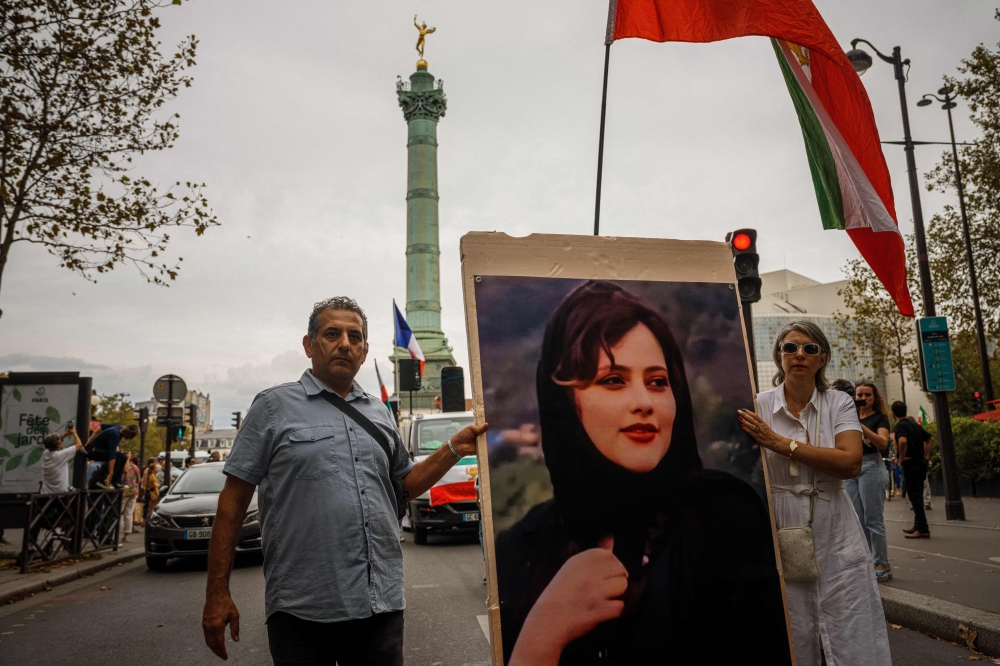 Demonstrators carry a portrait depicting late Mahsa Amini as they attend a protest against the Iranian regime in front of the Place de La Bastille in Paris. Yesterday marked the first anniversary of Mahsa’s death. — AFP