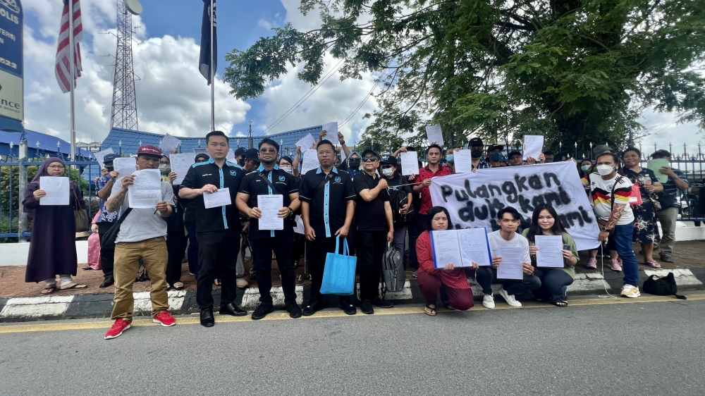 Hishamuddin (front, third left) and his MHO team together with the victims gather at the police headquarters in Jalan Badruddin. — Borneo Post Online pic