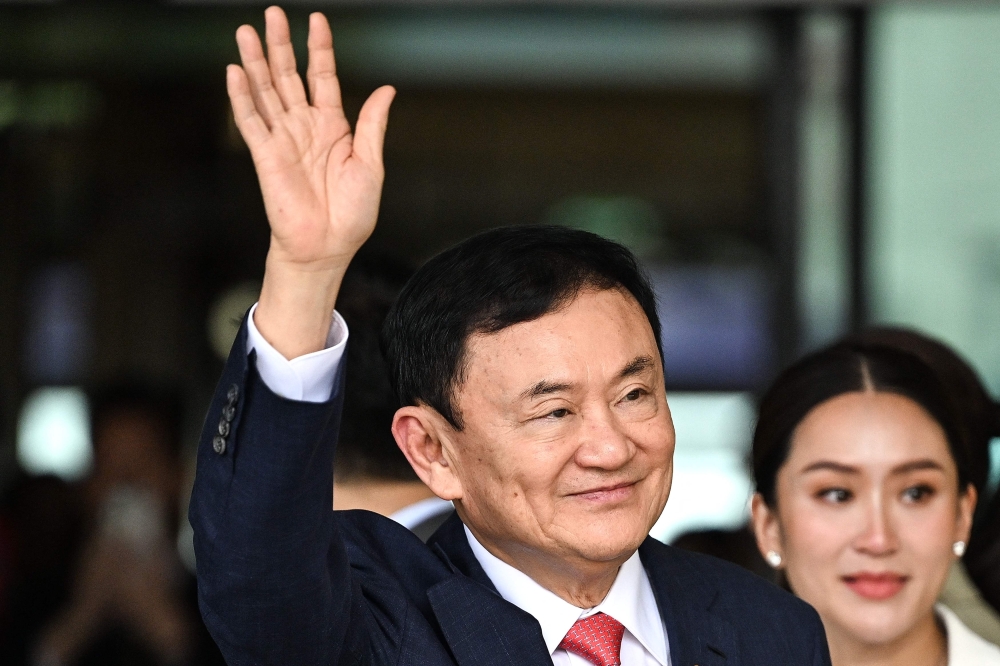 Former Thai Prime Minister Thaksin Shinawatra greets his supporters next to his daughter Paetongtarn Shinawatra (right) after landing at Bangkok's Don Mueang airport on August 22, 2023. Thaksin underwent surgery last week, his daughter said today, as his family mulls seeking his release on parole. — AFP pic