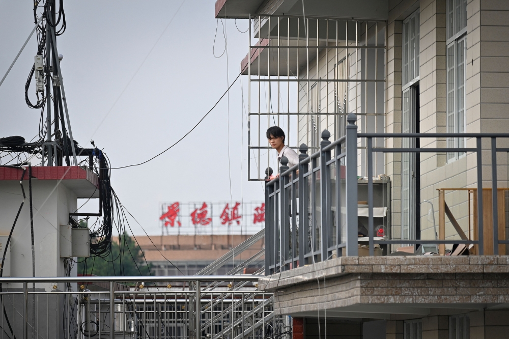 This picture taken on August 25, 2023 shows a man looking from his apartment in Jingdezhen. — AFP pic