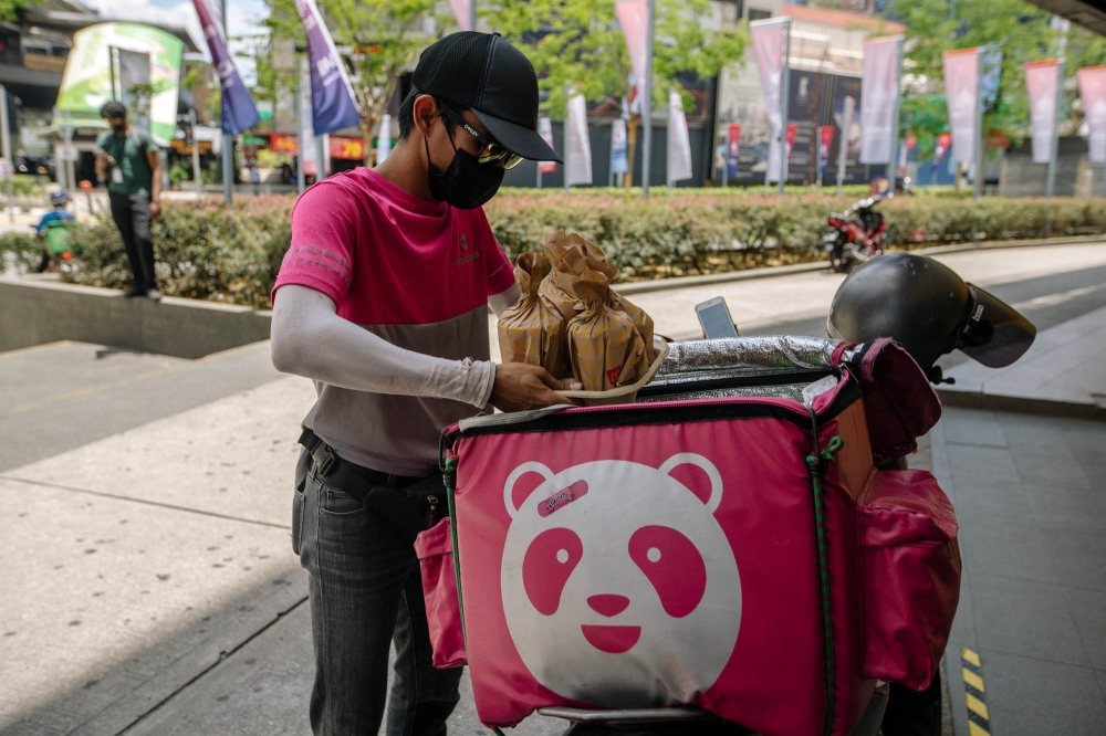 A delivery driver for Foodpanda rides puts an order in his bag in Kuala Lumpur March 22, 2021. — Picture by Firdaus Latif