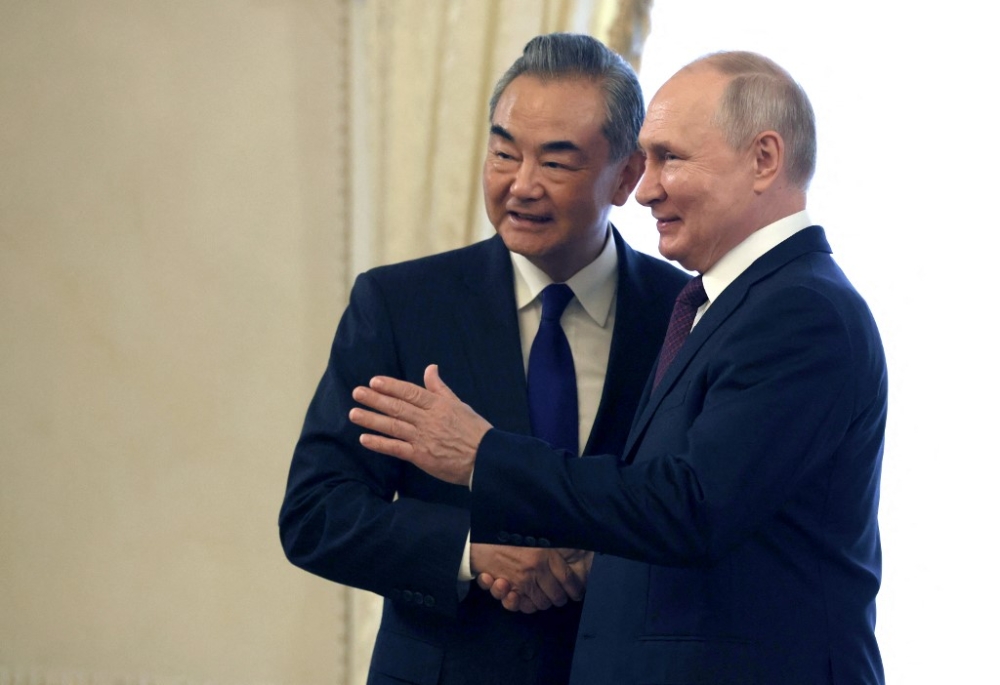 In this pool photograph distributed by Russian state-owned Sputnik agency on September 20, 2023, Russia's President Vladimir Putin (right) shakes hands with China's Foreign Minister Wang Yi, in Saint Petersburg. — AFP pic