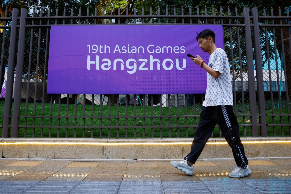 A person walks past a poster of Asian Games in Hangzhou, China. September 22, 2023. — Reuters pic