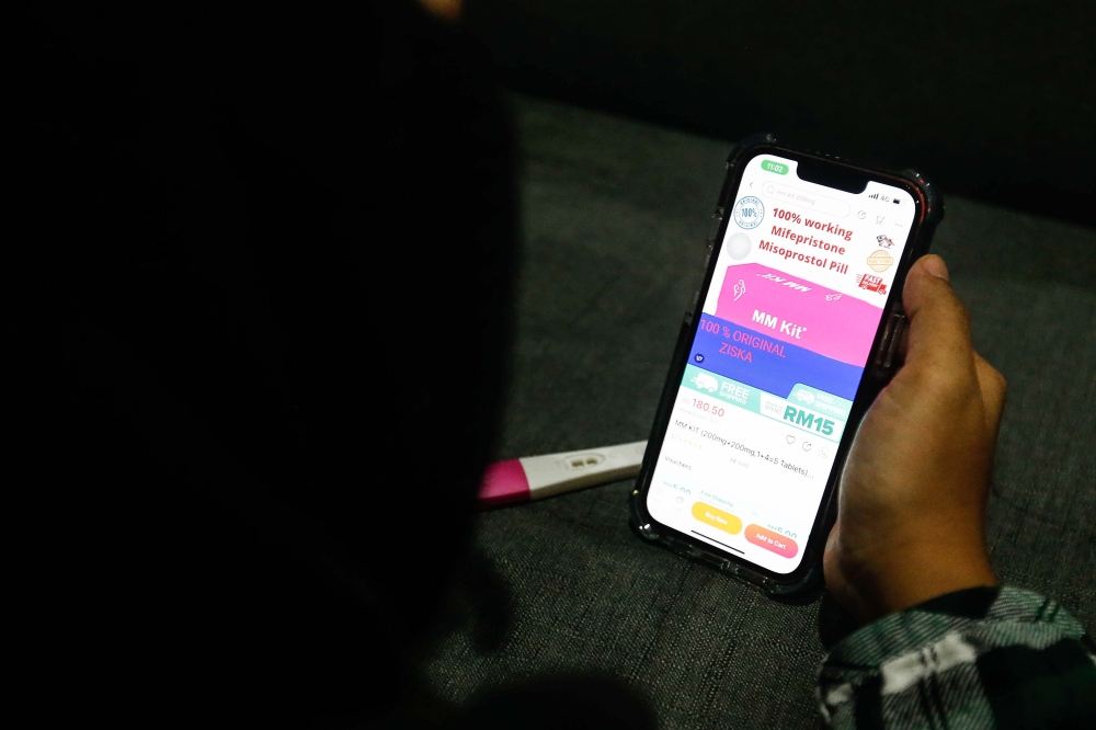 File photo of a woman pictured looking at her Pregnancy Test kit with positive result and Abortion Pills. — Picture by Sayuti Zainudin