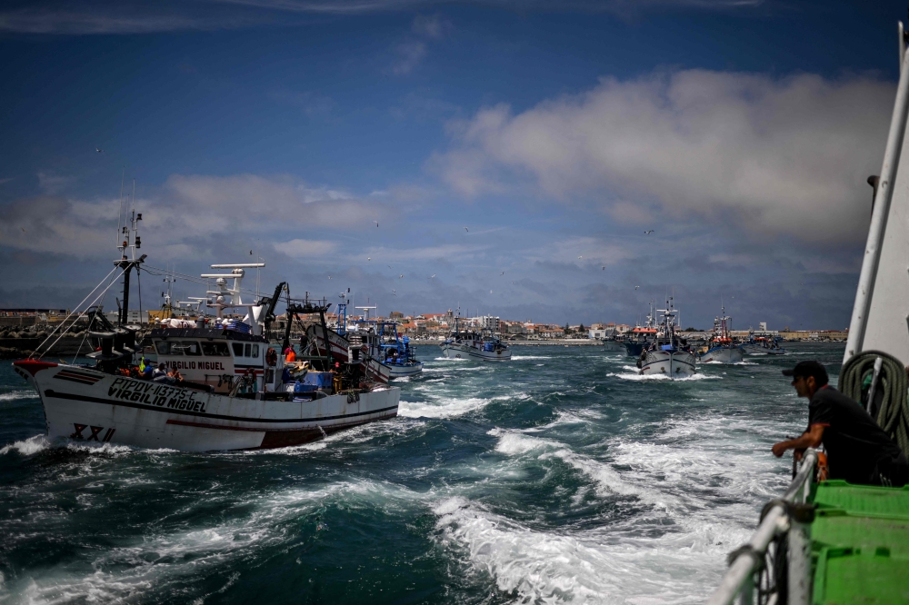 Fishing boats leave to start the sardine fishery from Peniche fishing port on June 16, 2023. An icon of the local festivities, that brings people together throughout the summer, sardines account for two-thirds of Portugal's fishing and provides the raw material for a major canning industry. — AFP pic