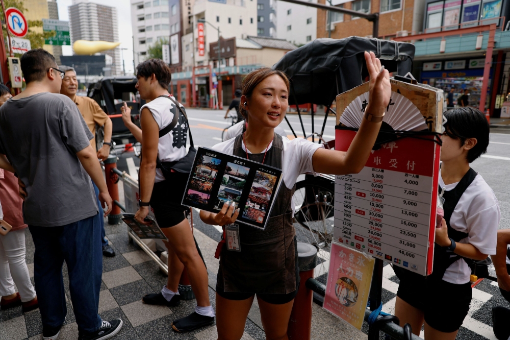 Rickshaw puller Shiori Yoshida, 28, attracts tourists to the guided tour at the Asakusa district in Tokyo, Japan, August 22, 2023. — Reuters pic