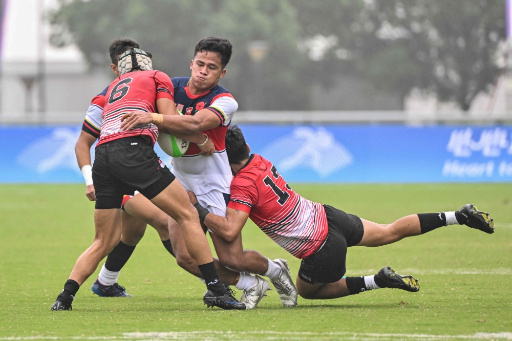 Malaysia’s Ahmad Zulhilmi (centre) fights for the ball with Singapore’s Bin Jeffrydin Muhammad Nur Hidayat (left) and Michael Andriesz in their men’s Rugby Seven match during the Hangzhou 2022 Asian Games in Hangzhou, in China’s eastern Zhejiang province on September 26, 2023. — AFP pic 