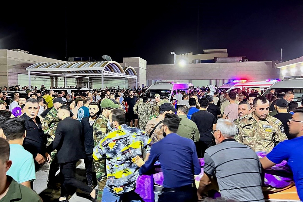Soldiers and emergency responders among others gather around ambulances carrying the wounded after a fire broke out at a wedding hall. — AFP pic