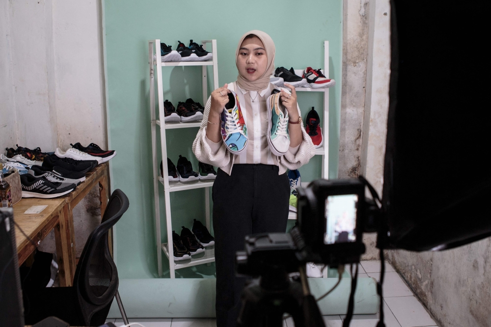 A staff of a small shoe manufacturer shows their new products to make an introductory video to be posted on social media in Bogor, West Java on 27 September 2023. — AFP pic