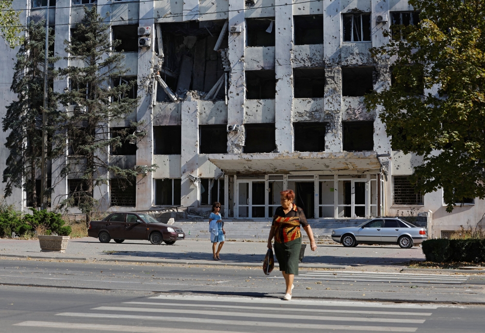 Women walk along a street near a building damaged in the course of Russia-Ukraine conflict in the city of Mariupol, Russian-controlled Ukraine September 28, 2023. ― Reuters pic