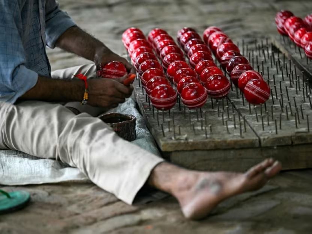 In this photograph taken on September 14, 2023, a worker polishes cricket balls at a workshop in Meerut in India's northern state of Uttar Pradesh. — AFP pi