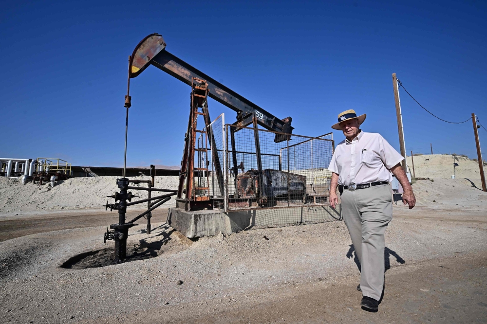 Third-generation oilman Fred Holmes walks past a working pumpjack at his oilfield in Taft, Kern County, California on September 21, 2023. — AFP pic