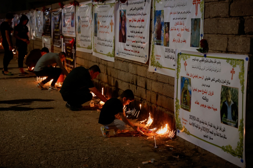 Christians light candles near pictures of victims of a fatal fire at a wedding celebration, in Hamdaniya, Iraq, September 29, 2023. — Reuters pic