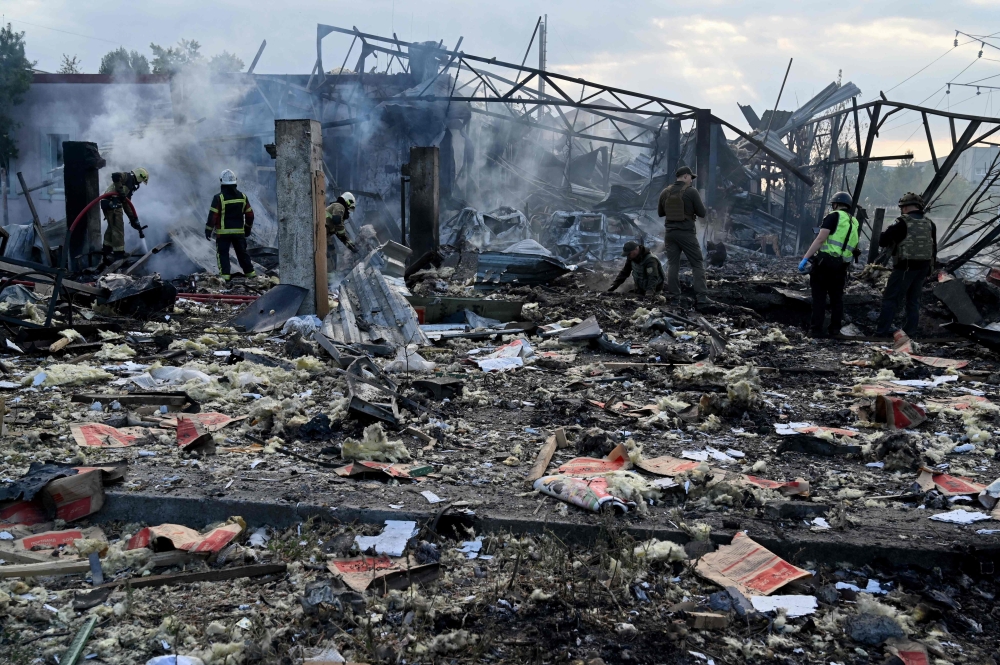 Firefighters push out a fire as police experts look for fragments of missile at a crater on an industrial area of the Ukrainian capital of Kyiv, after a massive overnight missile attack to Ukraine in this file picture taken on September 21, 2023. Two people were killed and 10 wounded in the latest Russian shelling of Kherson. — AFP pic