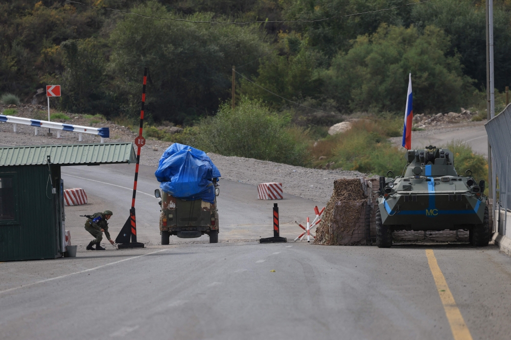 This photograph shows a Russian peacekeeper opening the gate for an Armenian vehicle leaving Karabakh at the Lachin checkpoint. — AFP pic
