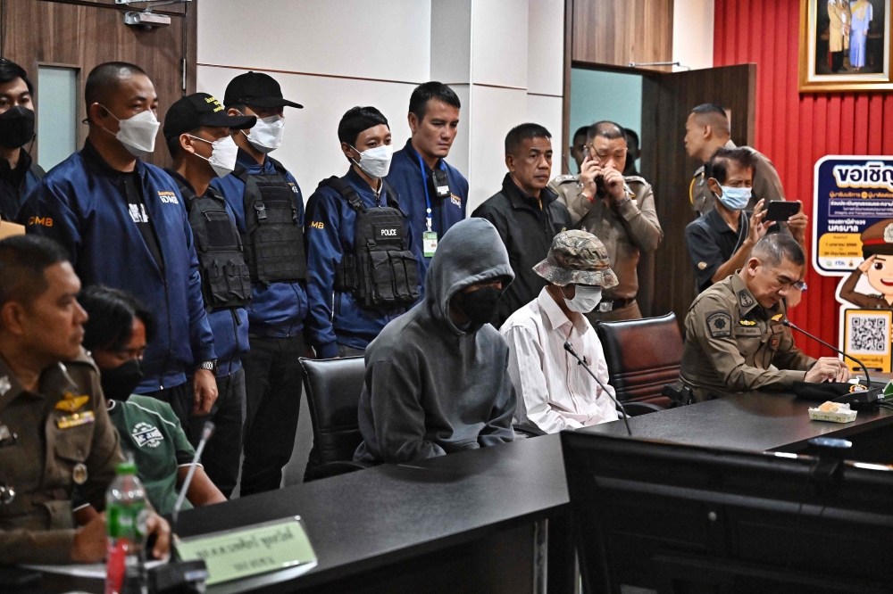 Two men accused of selling a gun to a 14-year-old suspected of carrying out a shooting attack at Bangkok Siam Paragon mall arrive for questioning at Yannawa Police Station in Bangkok on October 5, 2023. — AFP pic 