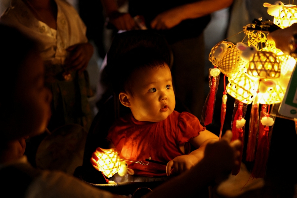 A child looks at lanterns sold at the Qinghefang Ancient Street, on the National Day Golden Week holiday in Hangzhou, China, October 2, 2023. — Reuters pic