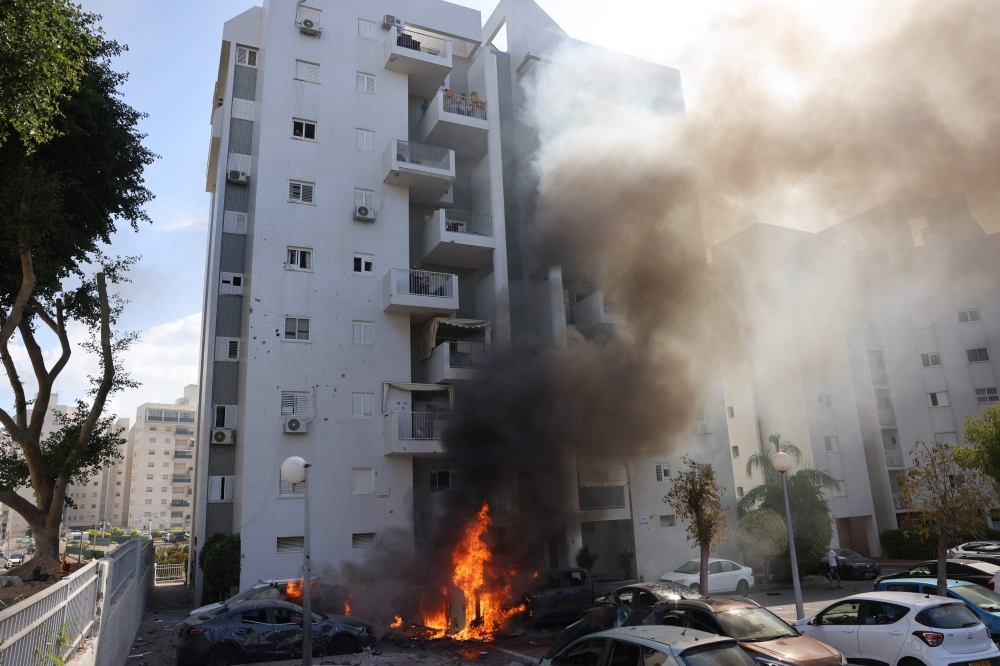 Cars parked outside a residential building catch fire during a rocket attack from the Gaza Strip on the southern Israeli city of Ashkelon, on October 7, 2023. — AFP pic