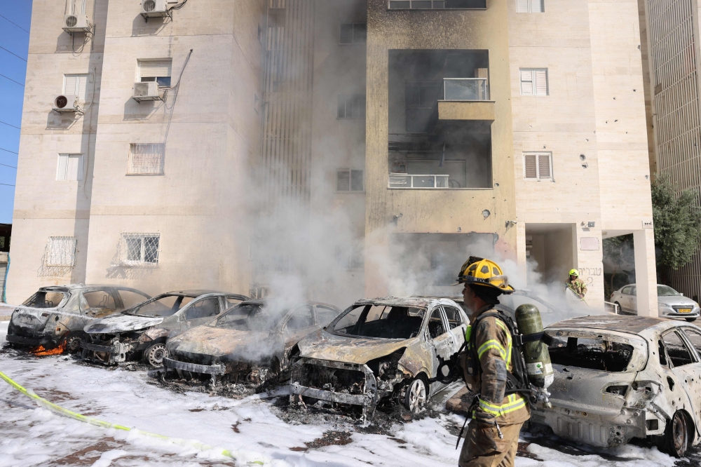 Israeli fire brigade teams douse the blaze in a partking lot outside a residential building following a rocket attack from the Gaza Strip in the southern Israeli city of Ashkelon, on October 7, 2023. — Reuters pic