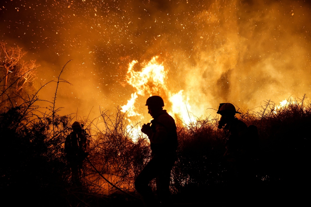 Firefighters work to put out a fire in an open field, following a mass-infiltration by Hamas gunmen. — Reuters pic