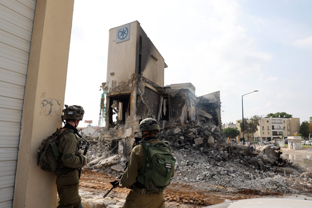 Soldiers stand in front of an Israeli police station that was damaged during battles the previous day to dislodge Hamas militants who were stationed inside, on October 8, 2023. — AFP pic