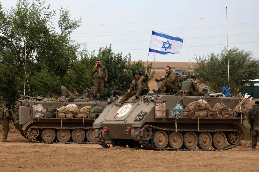 Israeli soldiers take positions in their armoured vehicles near the border with Gaza in southern Israel. — AFP pic