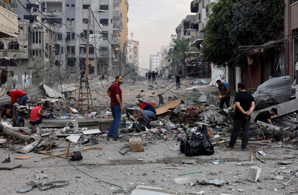 Palestinians inspect the damage in the aftermath of Israeli strikes, in Gaza City, October 11, 2023. — Reuters pic