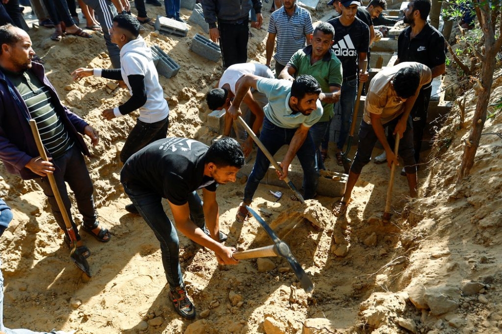 People dig graves to bury bodies of Palestinians from Samour family, who were killed in Israeli strikes on their house, at a land near to their home as the residents struggle to find spaces in cemeteries, in Khan Younis in the southern Gaza Strip October 12, 2023. — Reuters pic