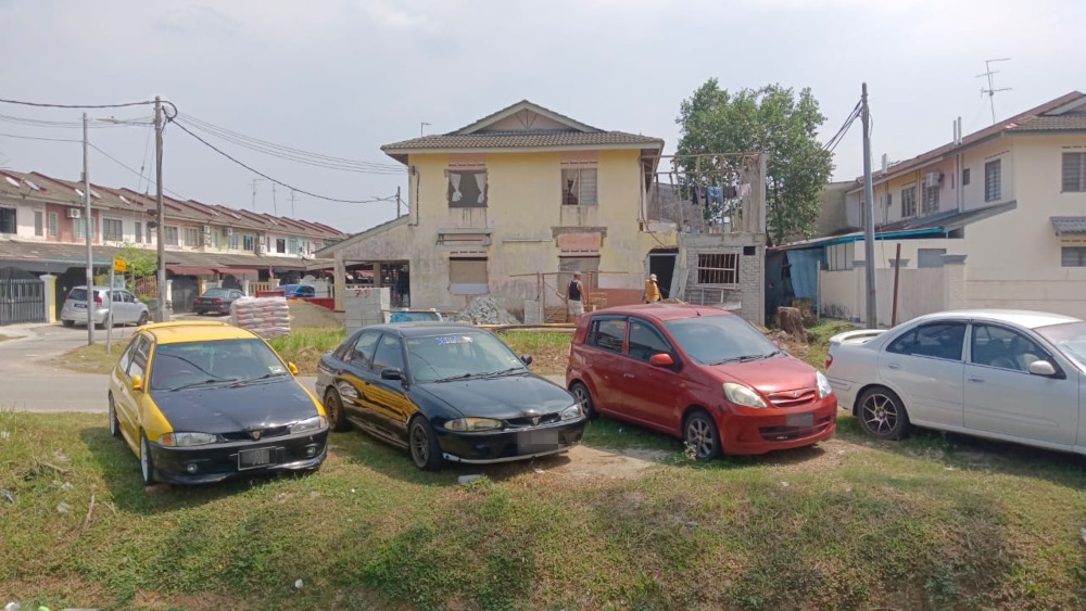 Residents’ cars that are parked on a patch of open land due to lack of parking spots in Taman Kota Masai in Pasir Gudang recently. — Picture by Ben Tan