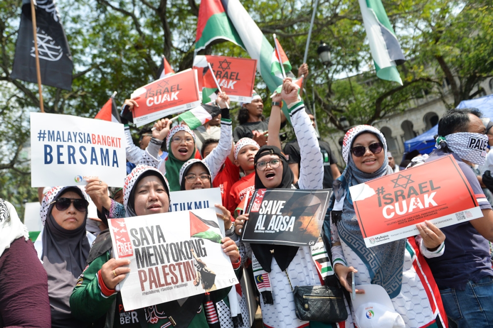People hold signs as they gather to protest against Israel, during the 'Free Palestine' rally at Masjid Negara in Kuala Lumpur October 13,2023. 