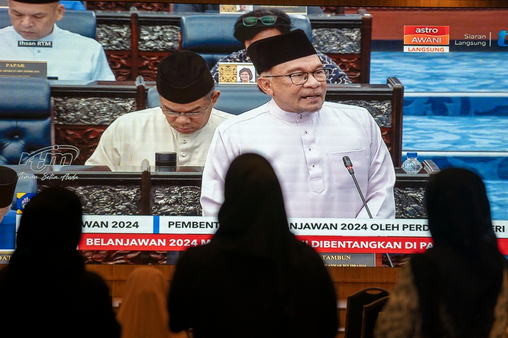 People watch the live telecast of Datuk Seri Anwar Ibrahim giving his Budget 2024 speech, October 13, 2023. — Picture by Shafwan Zaidon