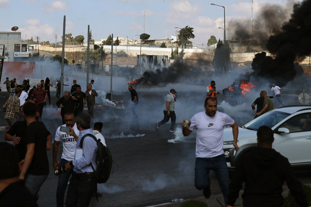 Palestinians scatter during clashes with Israeli soldiers at the north entrance of the Palestinian city of Ramallah, near Beit El Jewish settlement, in the occupied West Bank on October 13, 2023. ― AFP pic