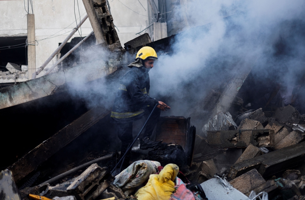 A rescue worker searches for casualties under the rubble in the aftermath of Israeli strikes, amid the ongoing conflict between Israel and the Palestinian Islamist group Hamas, in Khan Younis in the southern Gaza Strip, October 14, 2023. ― Reuters pic