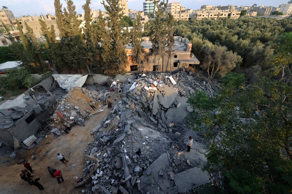 People inspect the damage to a building after Israeli strikes in the Rafah camp on the southern Gaza Strip on October 14, 2023. — AFP pic
