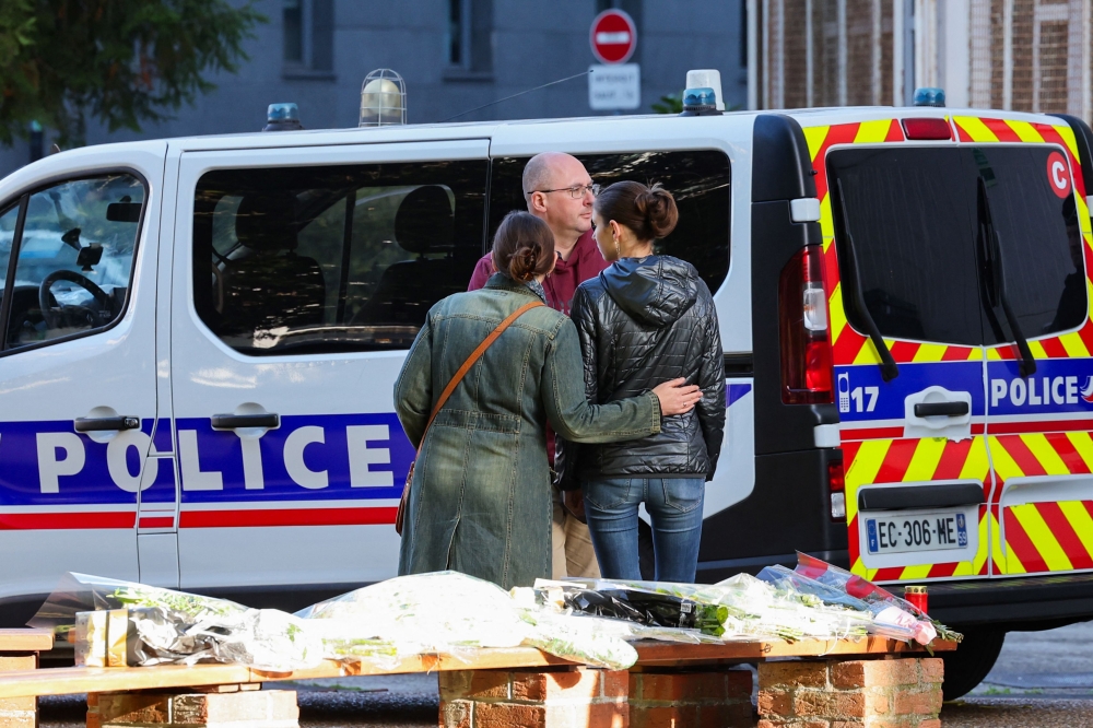 People gather to pay tribute in front of the Gambetta high school in Arras, northeastern France on October 14, 2023, the day after a teacher was killed and two other people severely wounded in a knife attack. — AFP pic