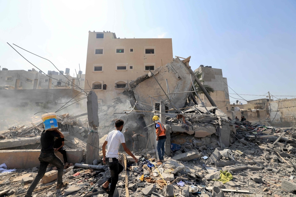Palestinians survey the rubble of a collapsed building following an Israeli strike, in Khan Yunis in the southern Gaza Strip on October 14, 2023, amid the ongoing battles between Israel and the Palestinian Islamist group Hamas. — AFP pic