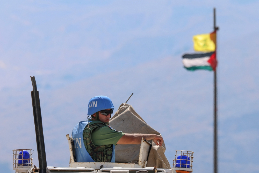The Palestinian flag and the flag of Hezbollah wave in the wind on a pole as peacekeepers from the United Nations Interim Force in Lebanon (UNIFIL) patrol the border area between Lebanon and Israel on Hamames hill in the Khiyam area of southern Lebanon, on October 13, 2023. — AFP pic