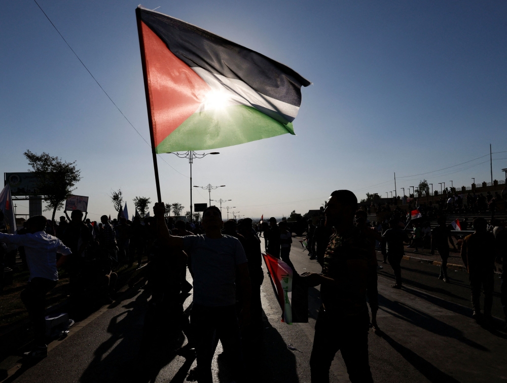 A man holds the Palestinian flag during a protest in solidarity with Palestinians in Gaza, in Mosul, Iraq, October 14, 2023. — Reuters pic