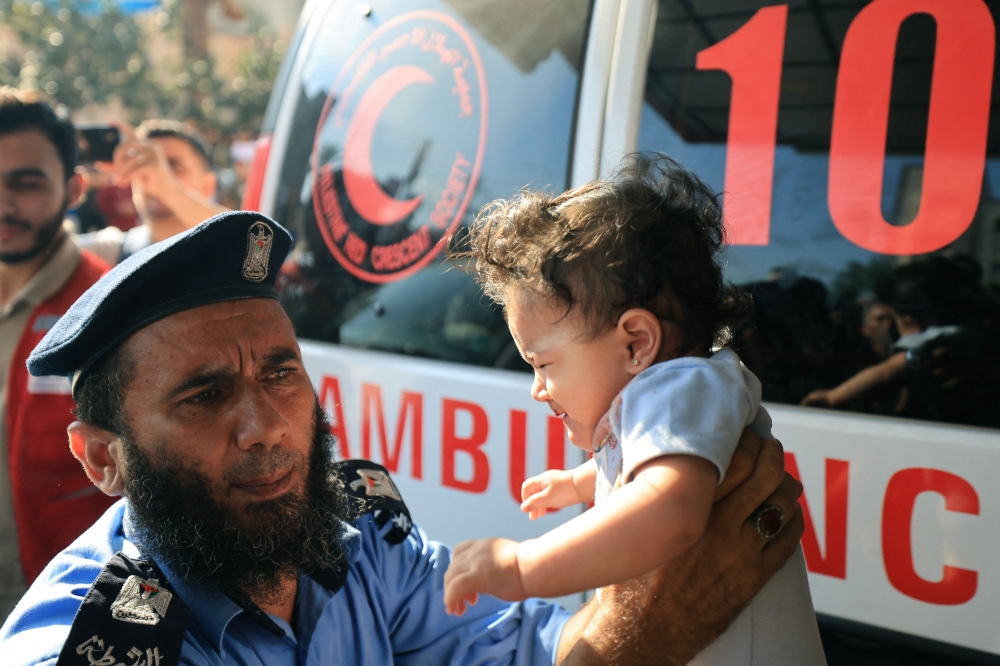 A Palestinian police officer holds a baby brought to a hospital following an Israeli strike, in Khan Yunis in the southern Gaza Strip on October 14, 2023, as fighting between Israel and the Hamas movement continues for the eighth consecutive day. — AFP pic