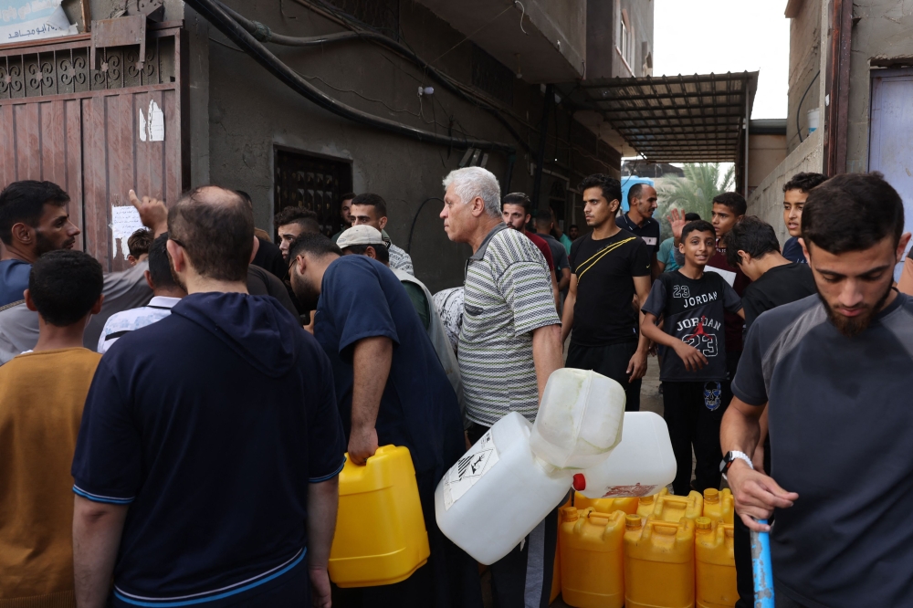 Palestinians queue to refill on water in Rafah refugee camp in the southern of Gaza Strip, on October 14, 2023. — AFP pic