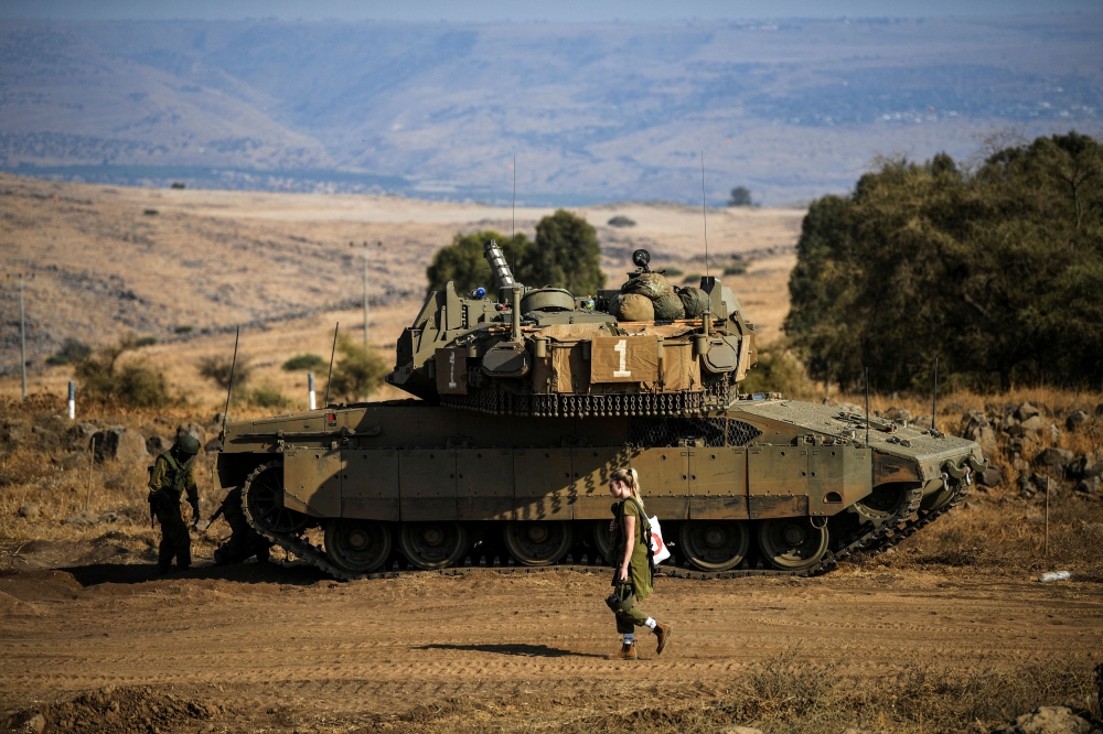 An Israeli soldier walks past a tank amid heightened tensions between Israel and Lebanon, as seen from the border with Lebanon in northern Israel, October 14, 2023. — Reuters pic