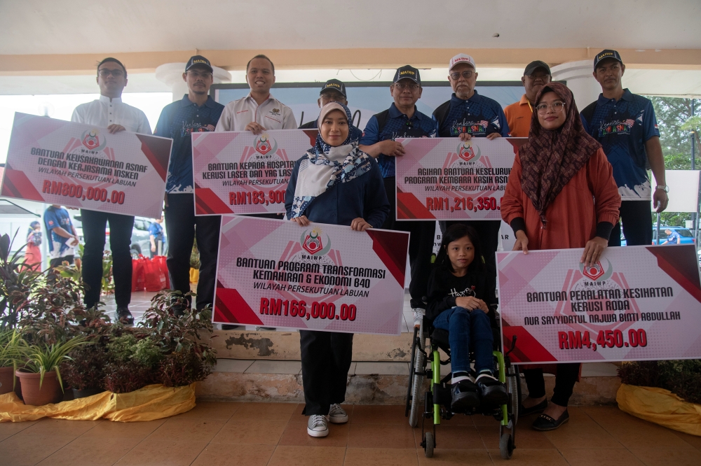 Minister in the Prime Minister’s Department (Religious Affairs) Datuk Mohd Na’im Mokhtar (back row, 4th right) poses for a picture with aid recipients during the Kembara Kasih Asnaf programme at Homestay Hall Kampung Sungai Labu, Labuan October 15, 2023. — Bernama pic