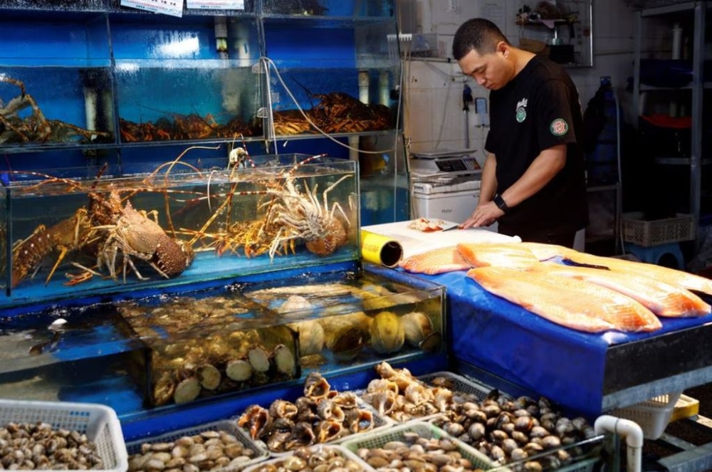 A vendor processes surf clams at a fish and seafood stall, at a seafood market in Beijing, China August 24, 2023. — Reuters pic