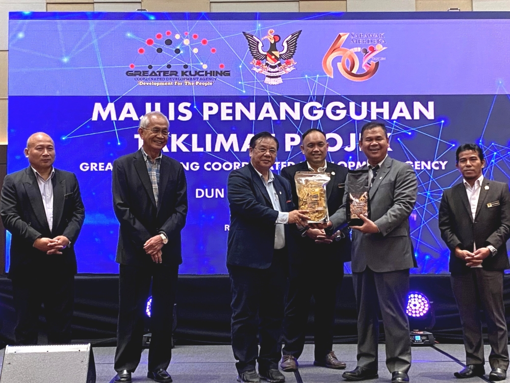 Dr Jerip (third left) presents coffee and banana chips products from Mambong to Ik Pahon (second, right) as mementos. ― Borneo Post pic