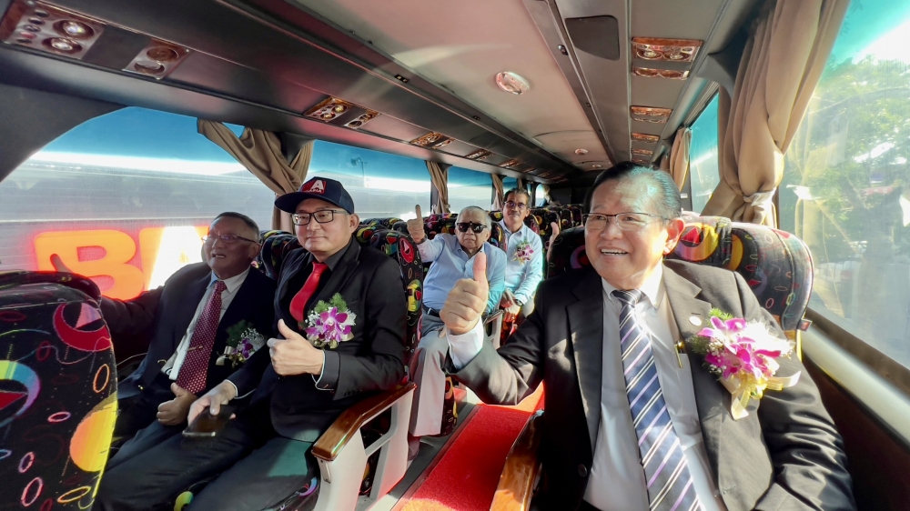 Datuk Seri Lee Kim Shin (right) shows a thumbs-up, with Sin Kiong (second, left), Abang Abdul Karim (sitting behind Sin Kiong) and others during a ride on the Bus Asia double-decker bus. — Picture by Roystein Emmor via Borneo Post